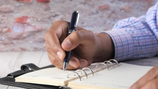 Gros plan de l'homme écriture à la main sur le bloc-notes. - Séquence, vidéo