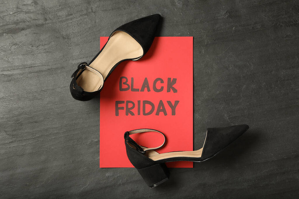 Elegant shoes and sheet of red paper with words Black Friday on dark background, flat lay - Fotografie, Obrázek