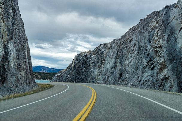 Дорога в лесу, скалы с обеих сторон с горами на заднем плане. Уинди Поинт. Alberta Highway 11 (David Thompson Hwy), Национальный парк Джаспер, Канада. - Фото, изображение