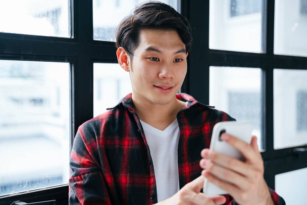 Asian young man using smartphone and smile. - Foto, Imagem