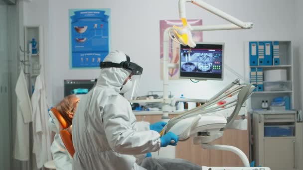 Dentista con schermo facciale che lavora in odontoiatria durante covid-19 - Filmati, video
