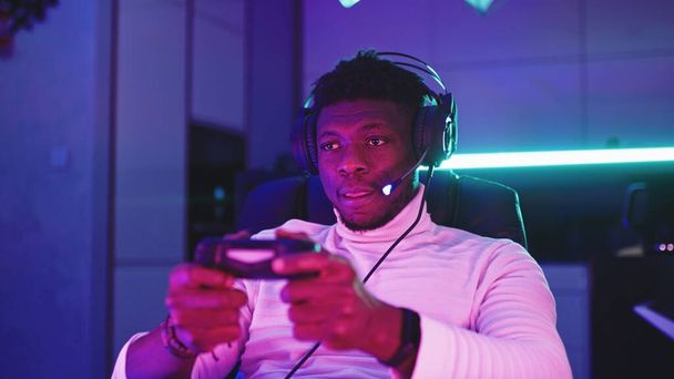 Odaklanmış genç siyahi adamın, video oyunları oynayan profesyonel oyun oyuncusunun portre çekimi - Fotoğraf, Görsel