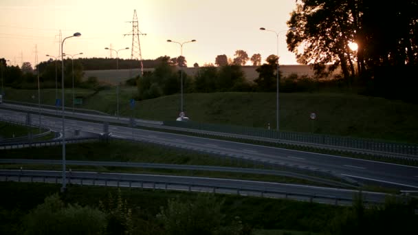 Hermoso paisaje de un tranquilo camino de cuatro carriles con coches durante la puesta del sol - Metraje, vídeo