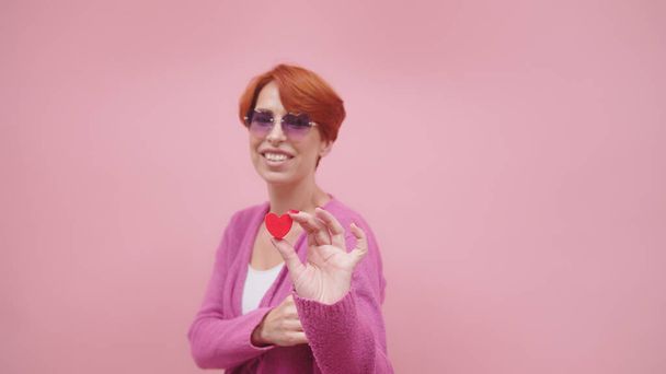 Rothaarige Frau mittleren Alters mit Herzform. Vereinzelt auf violettem Hintergrund - Foto, Bild