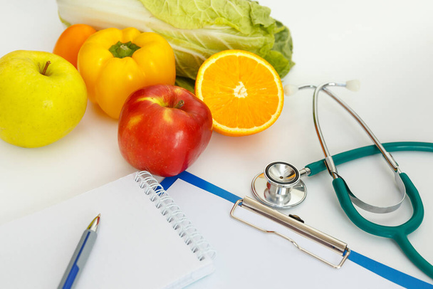 Nutrition and healthy eating. Fruits, vegetables, juice and stethoscope - Фото, изображение