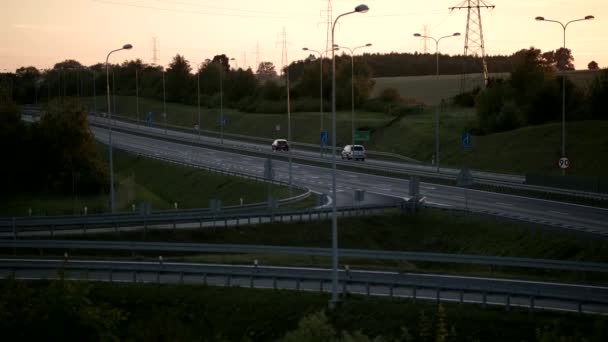Una toma panorámica de una tranquila carretera de cuatro carriles con coches durante la puesta del sol - Metraje, vídeo
