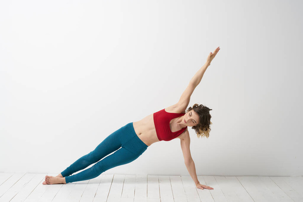 Жінка в блакитних джинсах практикує йогу на світлому фоні в приміщенні і тонку фігуру в гімнастиці
 - Фото, зображення