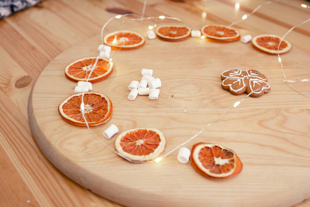 Girlanda, pianki i suszone pomarańcze na drewnianym okręgu. Przytulny świąteczny skład - Zdjęcie, obraz