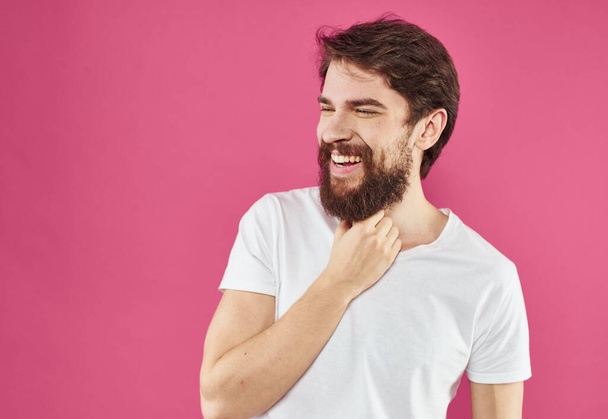 Happy man holds his hands near his face and laughs on a pink background - Photo, Image