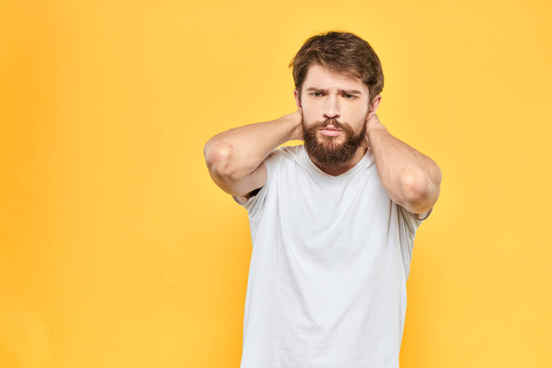 Бородатий чоловік в білій футболці жести з емоціями студії жовтого фону
 - Фото, зображення