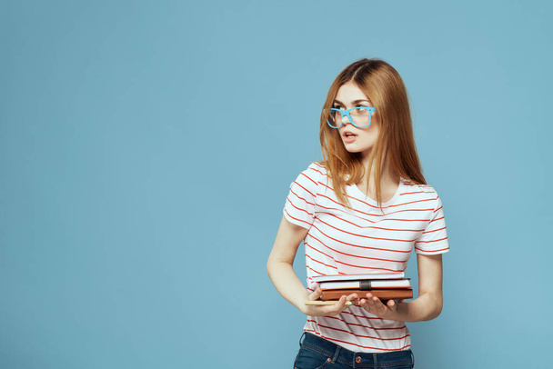девушка в модных очках с ноутбуками в руках на синем фоне обрезанный вид - Фото, изображение