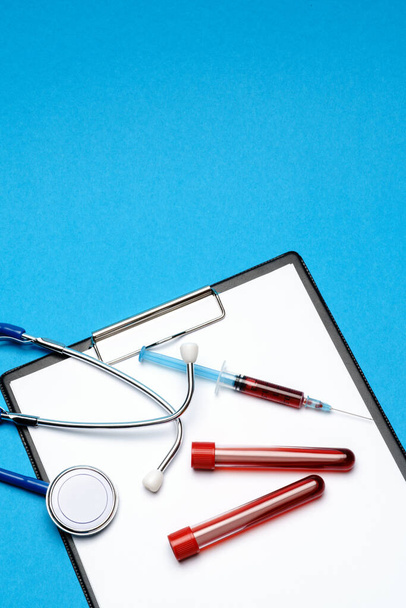 Healthcare concept - stethoscope, blood test tube, syringe and clipboard with blank sheet - Photo, Image