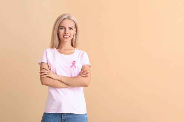 Молодая женщина с розовой лентой на цветном фоне. Концепция информированности о раке груди - Фото, изображение