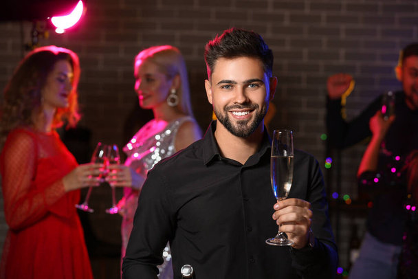 Young man with glass of tasty champagne at party in nightclub - Photo, Image