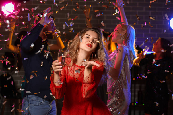 Gece kulübündeki partide elinde bir bardak lezzetli şampanya olan genç bir kadın. - Fotoğraf, Görsel