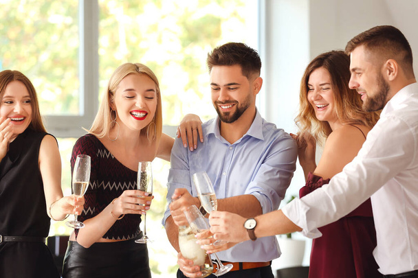 Młodzi ludzie piją smacznego szampana na imprezie w biurze - Zdjęcie, obraz