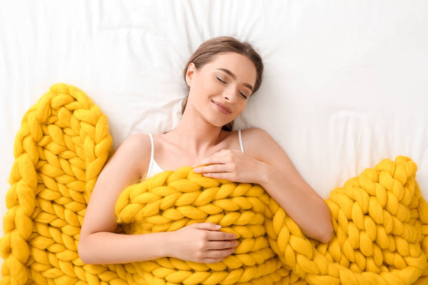 Šťastná mladá žena s teplou kostkovanou ležící na posteli, horní pohled - Fotografie, Obrázek
