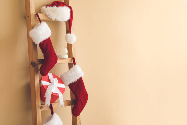 Létra karácsonyi ajándék, Mikulás kalap és zokni közelében színes fal - Fotó, kép
