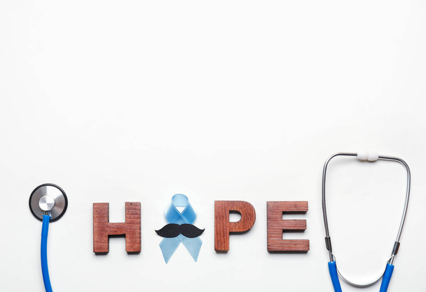 Palabra ESPERANZA, cinta azul, bigote y estetoscopio sobre fondo blanco. Concepto de conciencia del cáncer de próstata - Foto, imagen