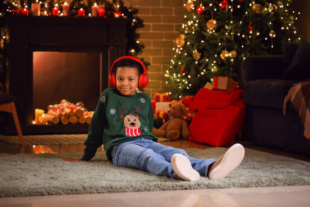Little African-American boy listening to music at home on Christmas eve - Фото, изображение