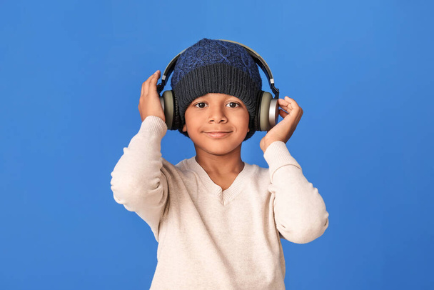 Little African-American boy listening to music on color background - Photo, Image