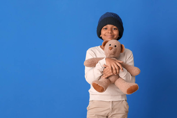 Cute African-American boy in winter clothes and with toy on color background - Photo, Image