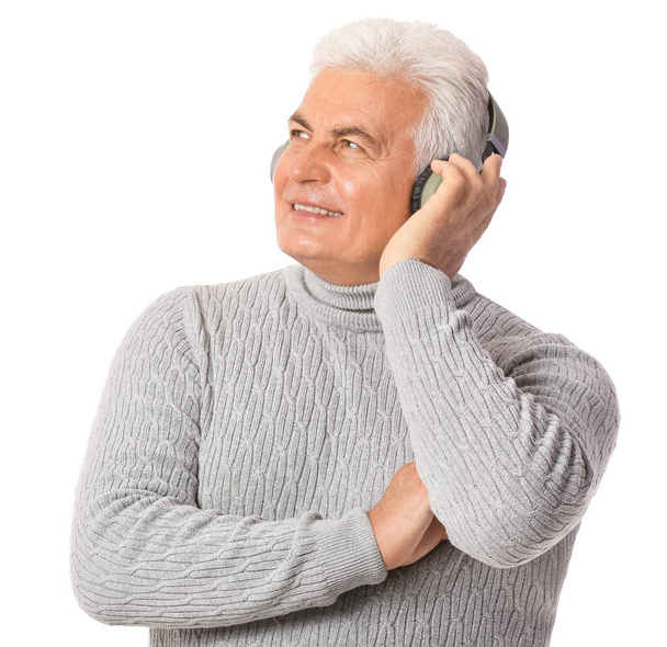 Mature man listening to music on white background - Foto, afbeelding