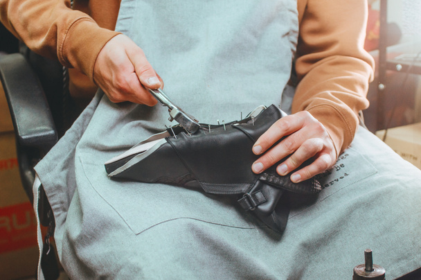 Закрытие сапожника, делающего обувь с помощью инструментов в мастерской - Фото, изображение