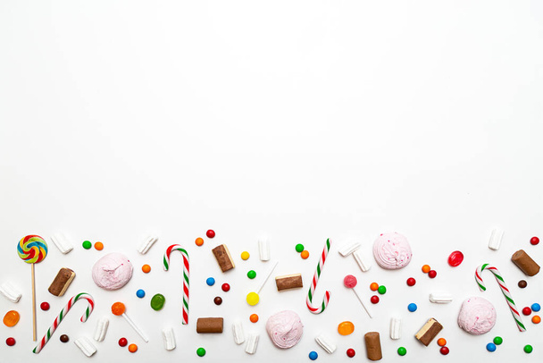 白い背景に様々な色のお菓子。ロリポップ、キャラメル、キャンディー、マシュマロ、チョコレート、クッキートップビュー - 写真・画像