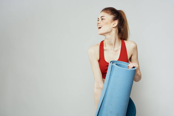 Kobieta trzyma w ręku matę do ćwiczeń fitness sport szczupła figura ćwiczenia lekkie tło - Zdjęcie, obraz