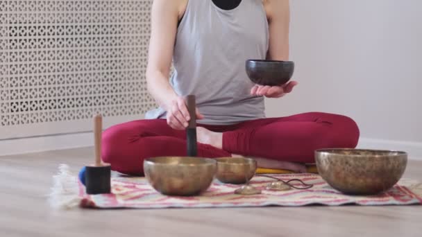 Kobieta grająca na tybetańskim talerzu podczas siedzenia na macie do jogi. Klasyczna tonacja. materiał filmowy. Filmik o zwolnionym tempie. Zamknij się. - Materiał filmowy, wideo