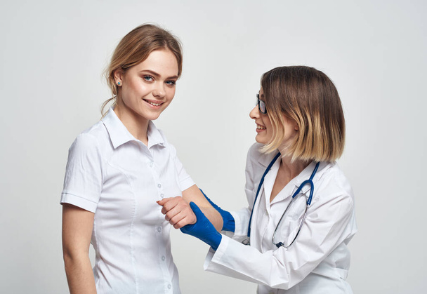 Ženský lékař v lékařských šatech a modrých rukavicích vyšetřuje pacienta v oříznutém pohledu - Fotografie, Obrázek