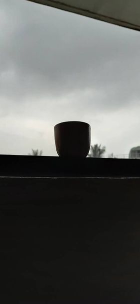 Gros plan d'argile artisanale ou de sable tasse de café traditionnelle près de la fenêtre avec arrière-plan extérieur - Photo, image