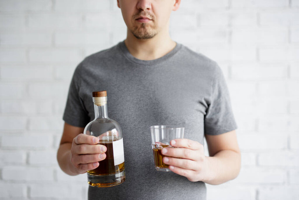 concepto de depresión y alcoholismo - vaso y botella de whisky en manos masculinas - Foto, Imagen