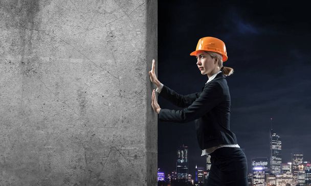 Beautiful woman architect pushing concrete wall - Фото, зображення