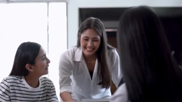 Jonge Aziatische vrouw die cadeautjes praat en praat met een vriend en wijst op een notitieboekje. Concept chatten met stagiaire bespreken sollicitatiegesprek collega 's hebben gesprek in kantoor genieten van teamwork. - Video