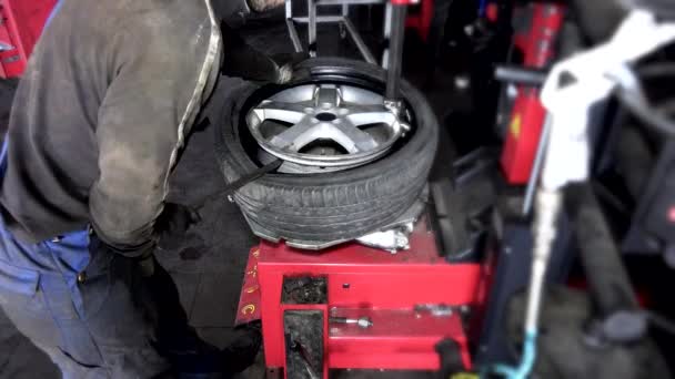 il riparatore lavora con pneumatico di ruota su bilanciatore a servizio di riparazione. 4K - Filmati, video