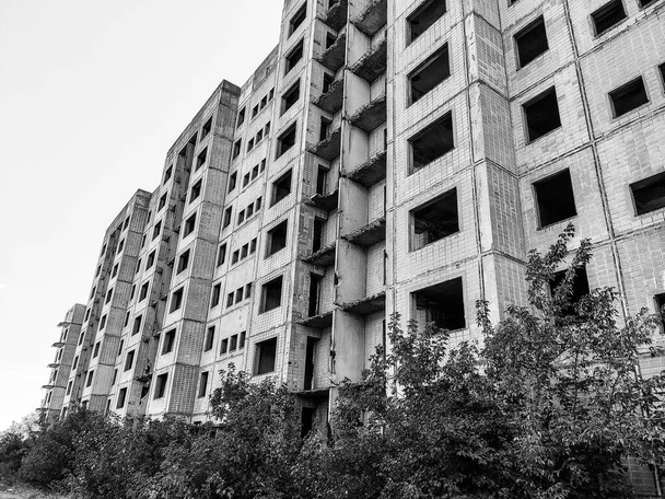 Korkea monikerroksinen hylätty Neuvostoliiton rakennuksen julkisivu kaatuneilla parvekkeilla mustavalkoisina. Weathered asunto estate, keskeneräinen kaupunki ydinfyysikkojen Birky, Ukraina - Valokuva, kuva
