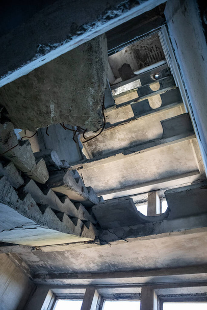 Crashed concrete staircase inside abandoned ruined building. Looking up the ruined weathered multistorey house - Photo, Image