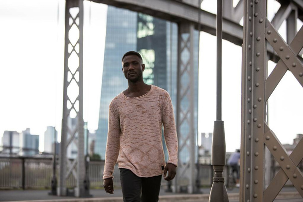Μοντέρνος μαύρος άντρας που φοράει πουλόβερ και περπατάει με αυτοπεποίθηση προς την κάμερα. Μήκος τριών τετάρτων.  - Φωτογραφία, εικόνα