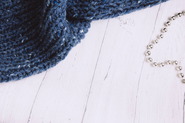 Синий вязаный свитер и серебряные бусины на светлом деревянном фоне. Концепция женского хобби. Игровая работа. Копирование пространства - Фото, изображение