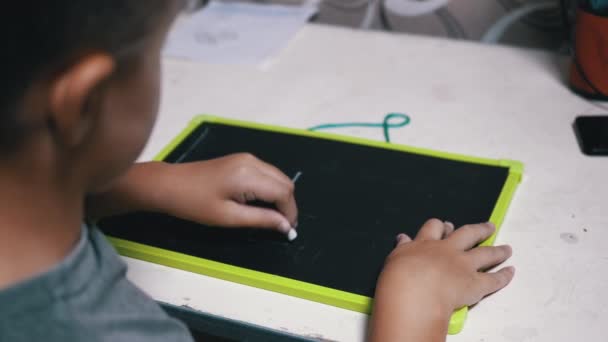 Tehetséges kréta fiú rajzol és ír leveleket egy fa táblára. Online tanulás - Felvétel, videó