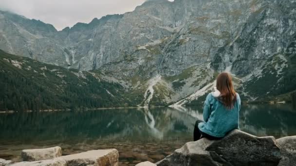Молодая туристка отдыхает на горном озере, наслаждается пейзажем высоко в горах. - Кадры, видео