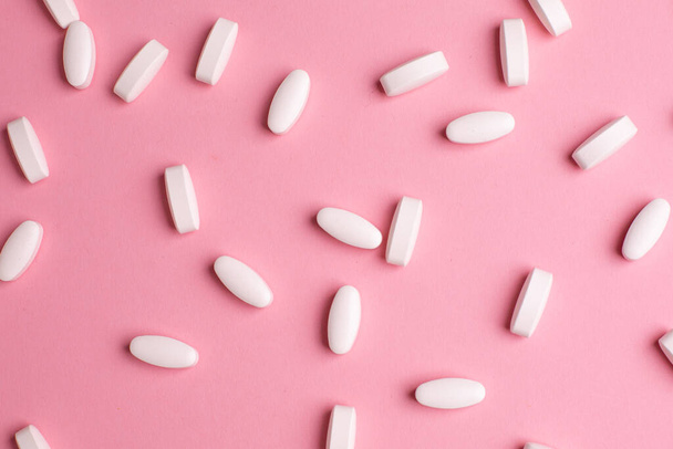 White vitamin pills to raise immunity on pink background, health and medical top view - Foto, Bild