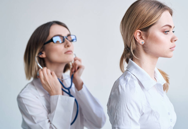 Профессиональный врач женщина со стетоскопом и пациентка вид сбоку - Фото, изображение