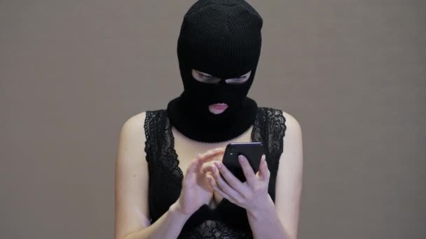 Σύζυγος ή φίλη με μαύρη μάσκα Balaclava χρησιμοποιούν κινητό τηλέφωνο του συζύγου της, γυναίκα με μεγάλα στήθη ντυμένος με εσώρουχα - Πλάνα, βίντεο