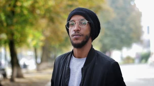 Portrait of mixed race man in glasses and a traditional hat, looking at camera, in slow motion - Footage, Video