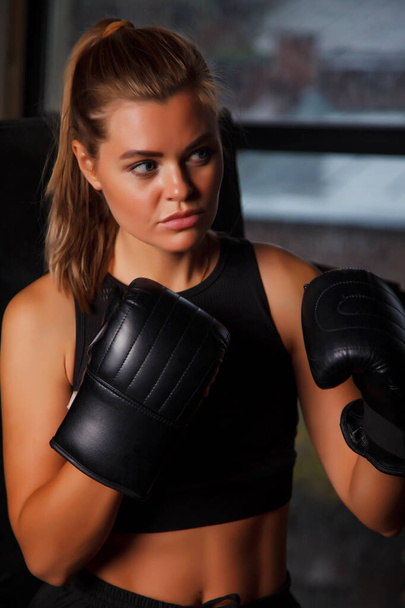 Pretty young female boxer stand in corner Boxing ring holding up hands in an old gym, her hand in gloves. Woman in box training. Concept of healthy lifestyle, sports and exercise in gym. Copy space - Zdjęcie, obraz