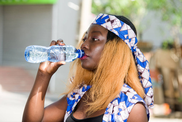 Genç bir kadın dışarıda durup şişede su içiyor.. - Fotoğraf, Görsel