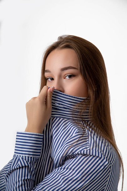 Young woman covers nose and mouth with a shirt instead of a mask for fear of bacteria and the COVID-19 virus - Foto, Bild